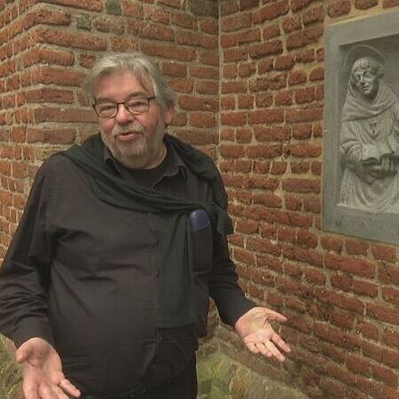 Foto Maarten van Rossum bij de reliefsteen van Bonifatius