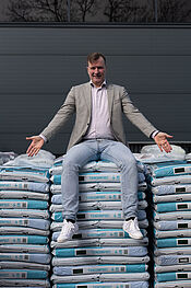 Wethouder Jeroen Brouwer zit op een stapel zakken compost